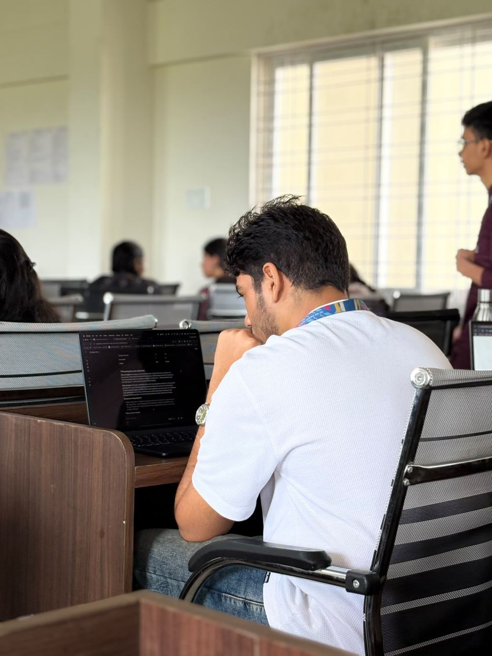 Victor at a laptop in a classroom, seen from behind, reviewing the deck