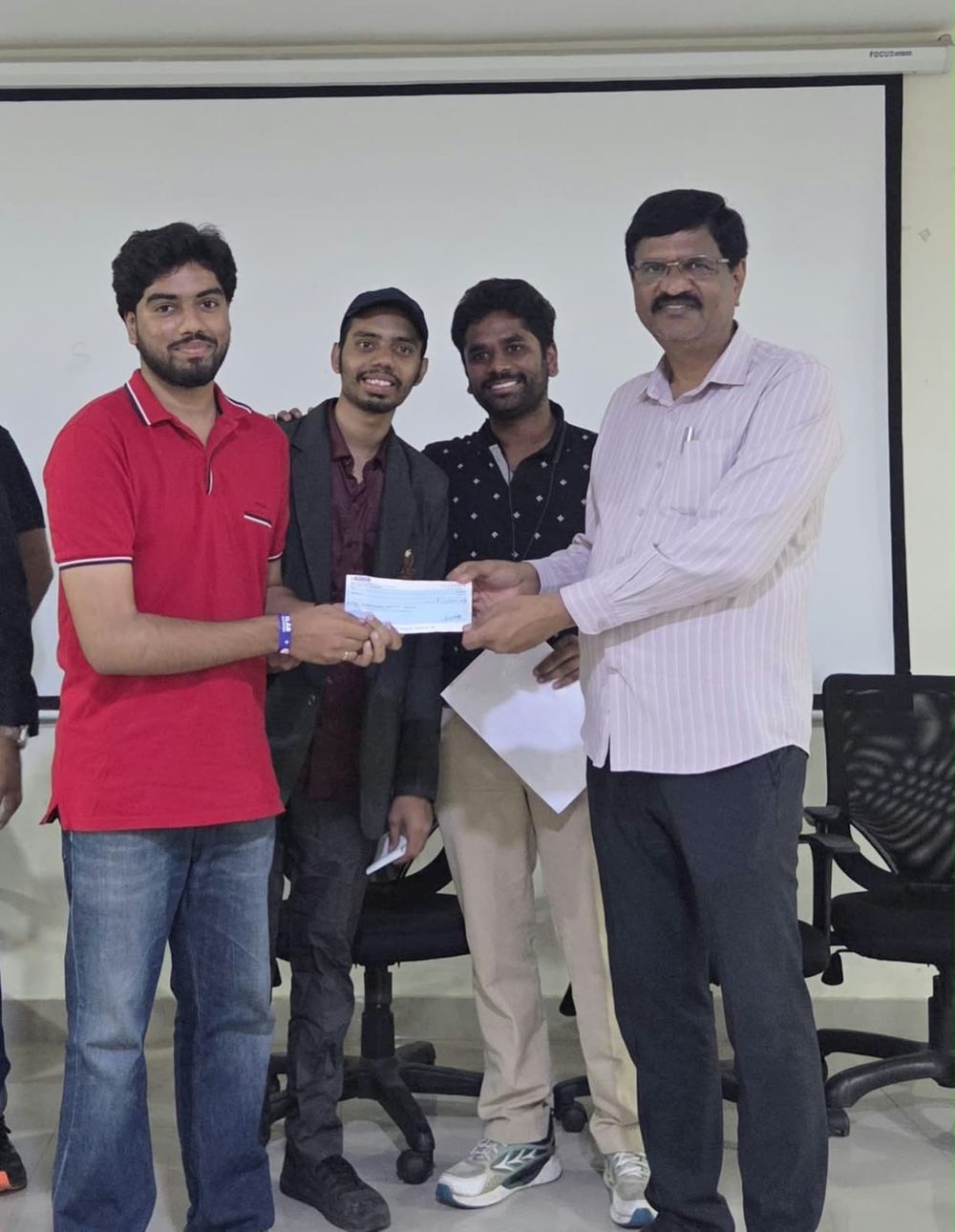 Victor in a red polo receiving the second-prize cheque at the SLAB Hackathon
