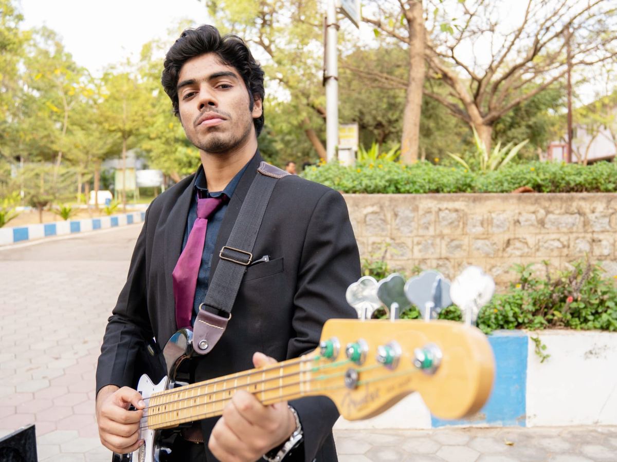Victor in a suit playing a Fender bass outdoors