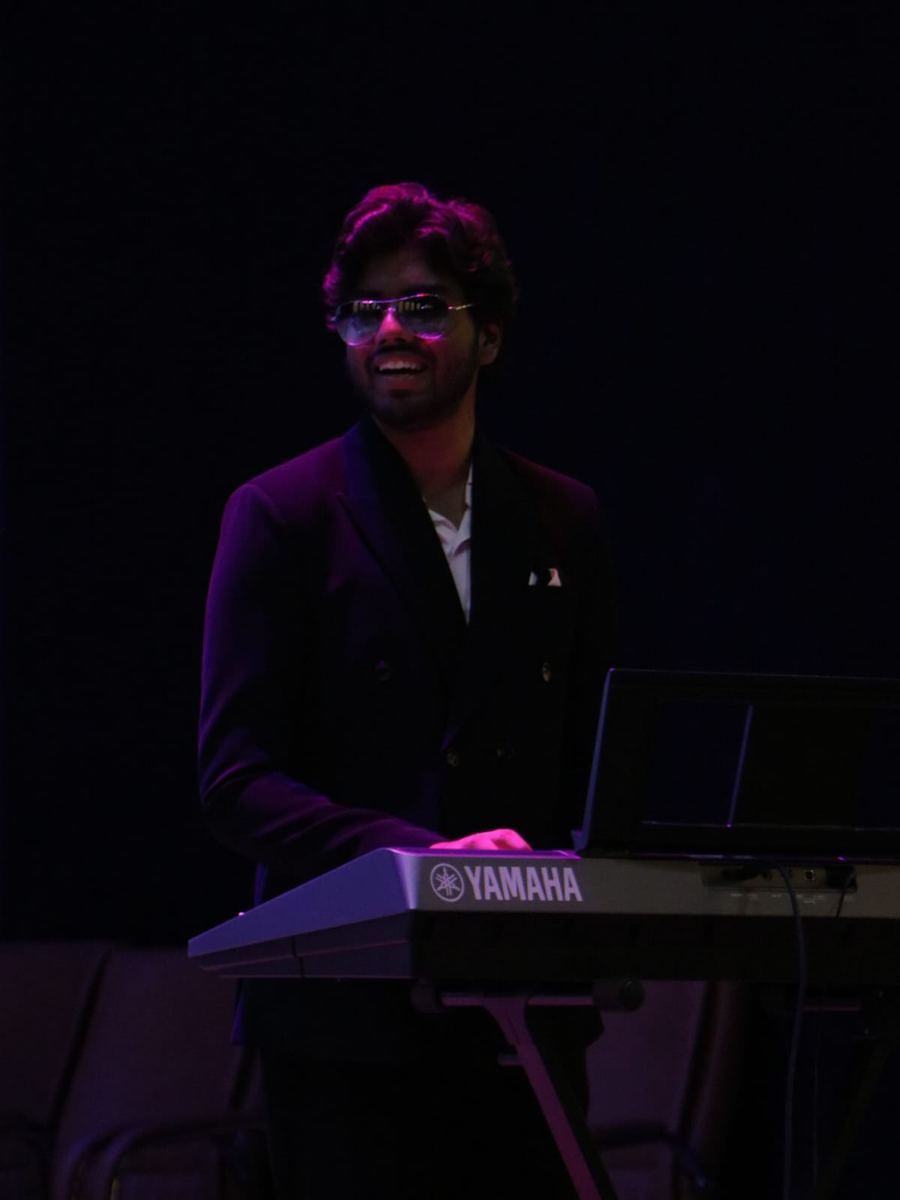 Victor smiling behind a Yamaha keyboard under purple stage light