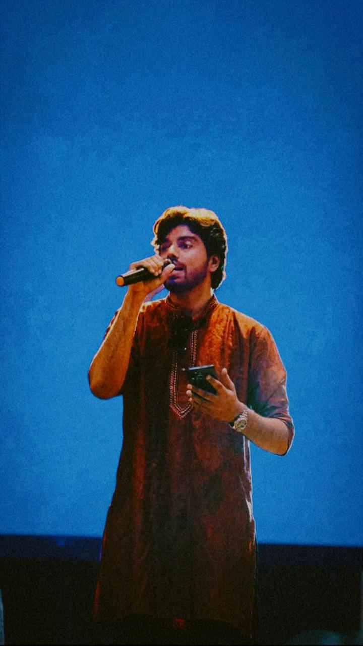 Victor singing into a microphone against a blue backdrop