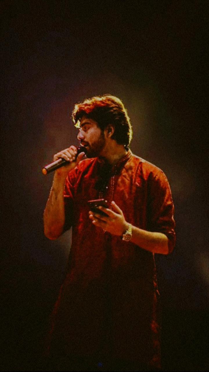 Victor singing in a red kurta under warm stage light