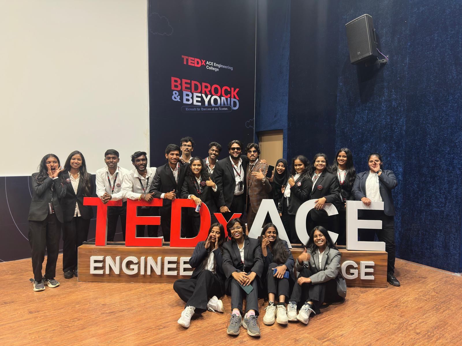 The TEDxACE organising committee posing behind the red and white TEDx ACE letters on stage