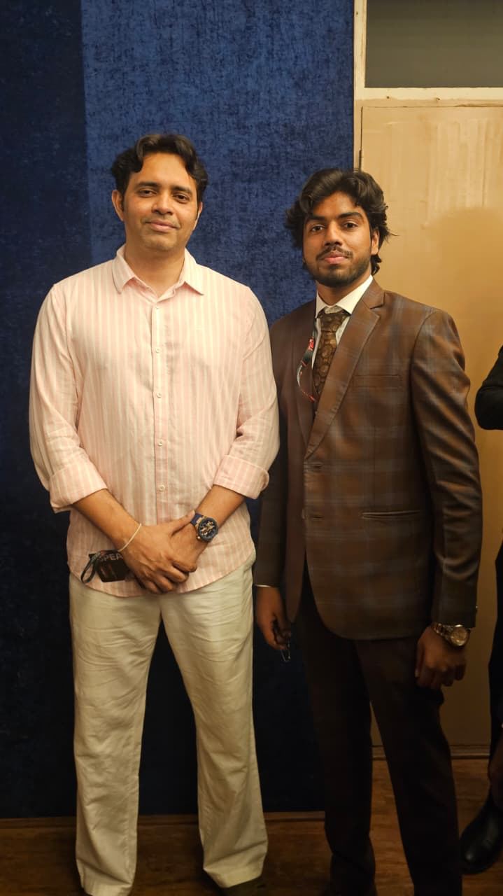 Victor in a brown suit standing beside Kaushik NC